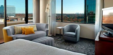 Sonesta Select Atlanta Cumberland Galleria double bed guest room, featuring sofa, chair, windows, and TV.