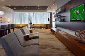 Sonesta Select Atlanta Cumberland Galleria’s lobby has a large, wall-mounted TV, comfortable seating, and coffee tables.