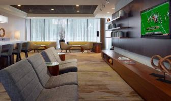 Sonesta Select Atlanta Cumberland Galleria’s lobby has a large, wall-mounted TV, comfortable seating, and coffee tables.