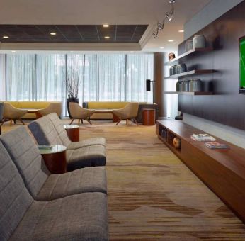 Sonesta Select Atlanta Cumberland Galleria’s lobby has a large, wall-mounted TV, comfortable seating, and coffee tables.