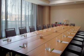 Hotel meeting room, with long wooden table, seating for over a dozen attendees, and large windows.