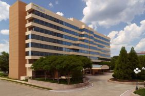 Sonesta Select Atlanta Cumberland Galleria’s exterior has the name on the building, numerous trees, and a covered entranceway.