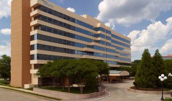 Sonesta Select Atlanta Cumberland Galleria’s exterior has the name on the building, numerous trees, and a covered entranceway.