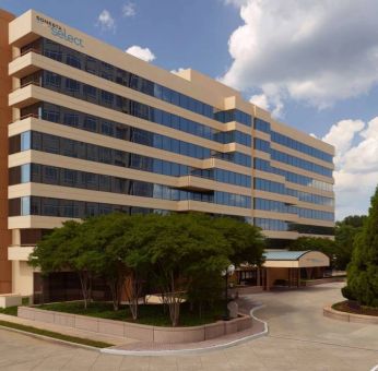 Sonesta Select Atlanta Cumberland Galleria’s exterior has the name on the building, numerous trees, and a covered entranceway.