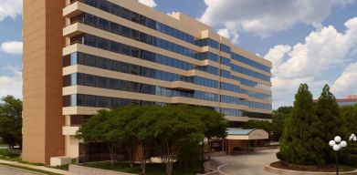 Sonesta Select Atlanta Cumberland Galleria’s exterior has the name on the building, numerous trees, and a covered entranceway.