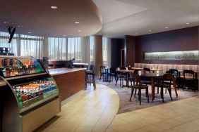 Sonesta Select Atlanta Cumberland Galleria’s dining area features a bar, both tall stool and table seating, and large windows.