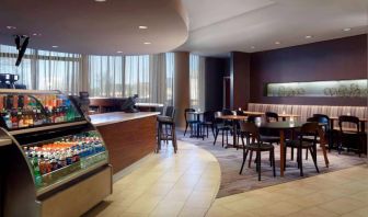 Sonesta Select Atlanta Cumberland Galleria’s dining area features a bar, both tall stool and table seating, and large windows.