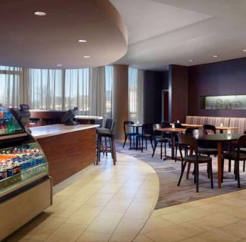 Sonesta Select Atlanta Cumberland Galleria’s dining area features a bar, both tall stool and table seating, and large windows.