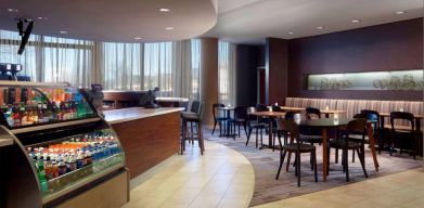 Sonesta Select Atlanta Cumberland Galleria’s dining area features a bar, both tall stool and table seating, and large windows.