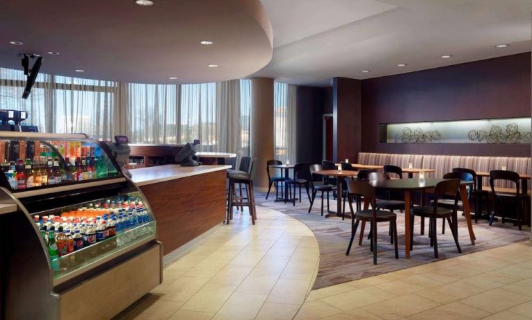 Sonesta Select Atlanta Cumberland Galleria’s dining area features a bar, both tall stool and table seating, and large windows.