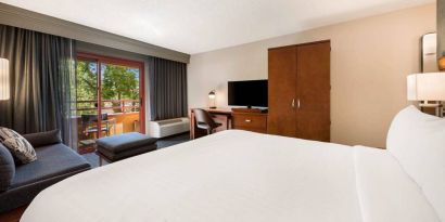 Double bed guest room in Sonesta Select San Jose Airport, with workspace desk and chair, plus TV.