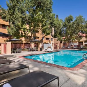 The outdoor pool at Sonesta Select San Jose Airport features a lift, and has nearby sun loungers and shaded tables and chairs.