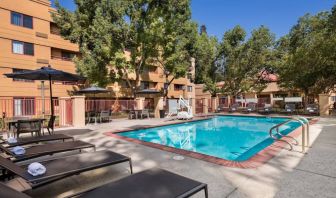 The outdoor pool at Sonesta Select San Jose Airport features a lift, and has nearby sun loungers and shaded tables and chairs.