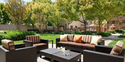 The hotel’s patio has trees nearby, and a mix of sofa and armchair seating.