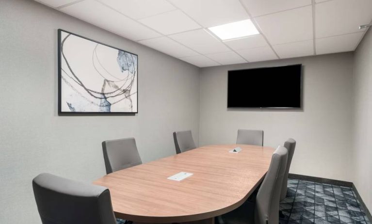 Hotel meeting room, with half a dozen chairs set around a wooden table, and a large TV on the wall.