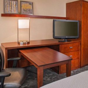 Guest room workspace in Sonesta Select Charlotte University Research Park, including desk, chair, and television.