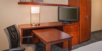 Guest room workspace in Sonesta Select Charlotte University Research Park, including desk, chair, and television.