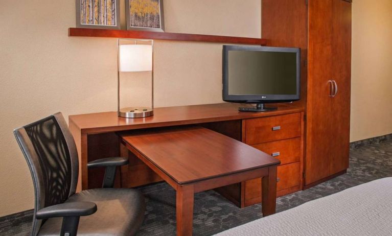 Guest room workspace in Sonesta Select Charlotte University Research Park, including desk, chair, and television.