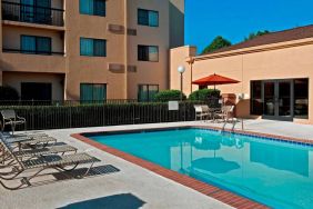 Sonesta Select Charlotte University Research Park’s outdoor pool has sun loungers and a shaded table and chairs by the side.