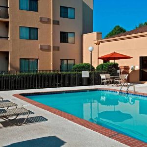 Sonesta Select Charlotte University Research Park’s outdoor pool has sun loungers and a shaded table and chairs by the side.