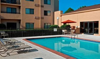 Sonesta Select Charlotte University Research Park’s outdoor pool has sun loungers and a shaded table and chairs by the side.