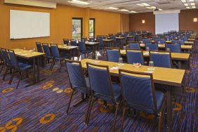 Hotel meeting room, featuring tables arranged in a classroom style facing a projector screen, with a whiteboard to one side.