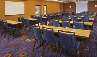 Hotel meeting room, featuring tables arranged in a classroom style facing a projector screen, with a whiteboard to one side.