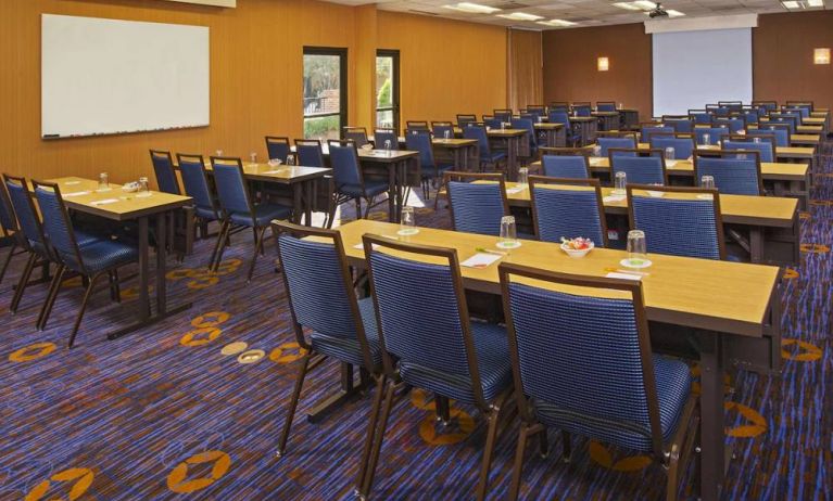 Hotel meeting room, featuring tables arranged in a classroom style facing a projector screen, with a whiteboard to one side.