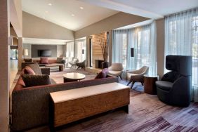 The lobby lounge in Sonesta Select Boston Milford includes chairs, sofas, and coffee tables, plus large windows.