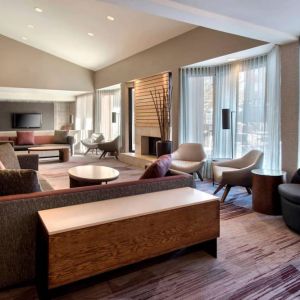 The lobby lounge in Sonesta Select Boston Milford includes chairs, sofas, and coffee tables, plus large windows.