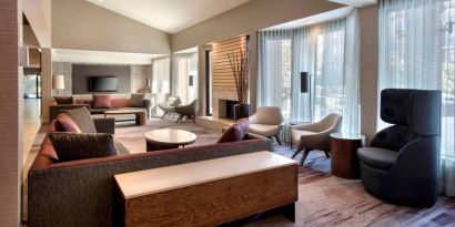 The lobby lounge in Sonesta Select Boston Milford includes chairs, sofas, and coffee tables, plus large windows.