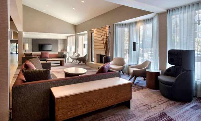 The lobby lounge in Sonesta Select Boston Milford includes chairs, sofas, and coffee tables, plus large windows.