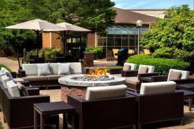 The hotel’s fire pit is surrounded by sofas and armchairs, and plenty of coffee tables, with pleasant greenery in the background.