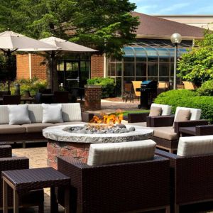 The hotel’s fire pit is surrounded by sofas and armchairs, and plenty of coffee tables, with pleasant greenery in the background.