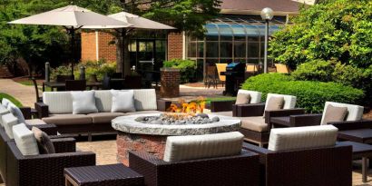 The hotel’s fire pit is surrounded by sofas and armchairs, and plenty of coffee tables, with pleasant greenery in the background.