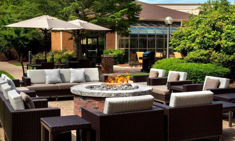 The hotel’s fire pit is surrounded by sofas and armchairs, and plenty of coffee tables, with pleasant greenery in the background.