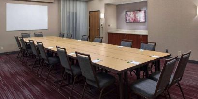 Meeting room in Sonesta Select Boston Milford, furnished with seating for 16 attendees, a long table, and a whiteboard.