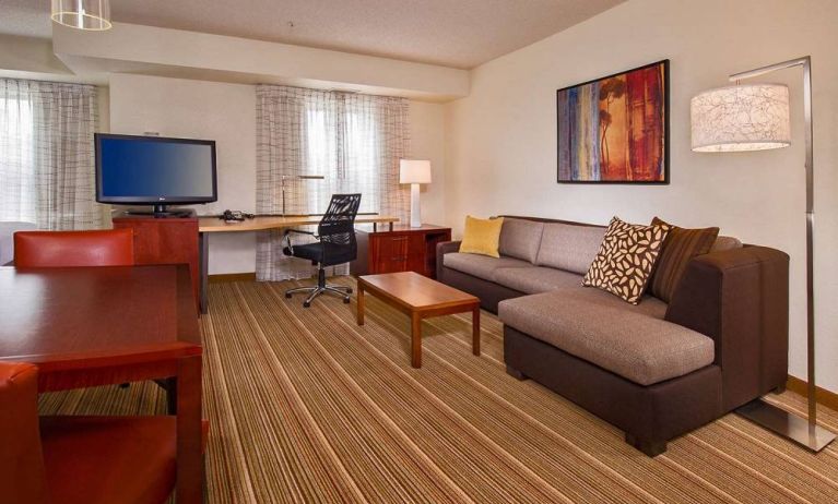 Sonesta ES Suites Charlottesville University guest room workspace, furnished with desk, chair, and TV, plus a sofa.