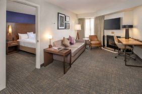 Double bed guest room in Sonesta ES Suites Baltimore BWI Airport, furnished with sofa, chair, fireplace, and television.