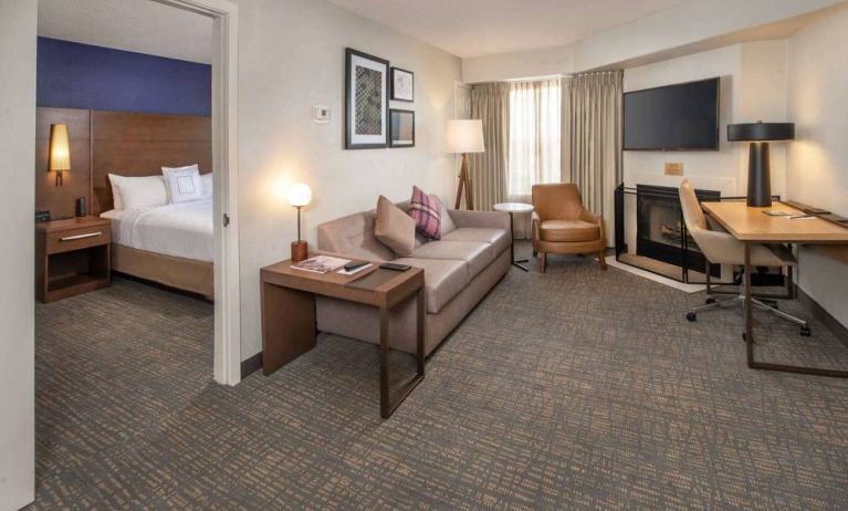 Double bed guest room in Sonesta ES Suites Baltimore BWI Airport, furnished with sofa, chair, fireplace, and television.