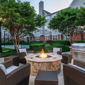 Sonesta ES Suites Baltimore BWI Airport’s fire pit is surrounded by armchairs and coffee tables, with a barbecue conveniently close.