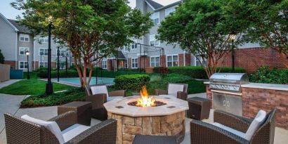 Sonesta ES Suites Baltimore BWI Airport’s fire pit is surrounded by armchairs and coffee tables, with a barbecue conveniently close.