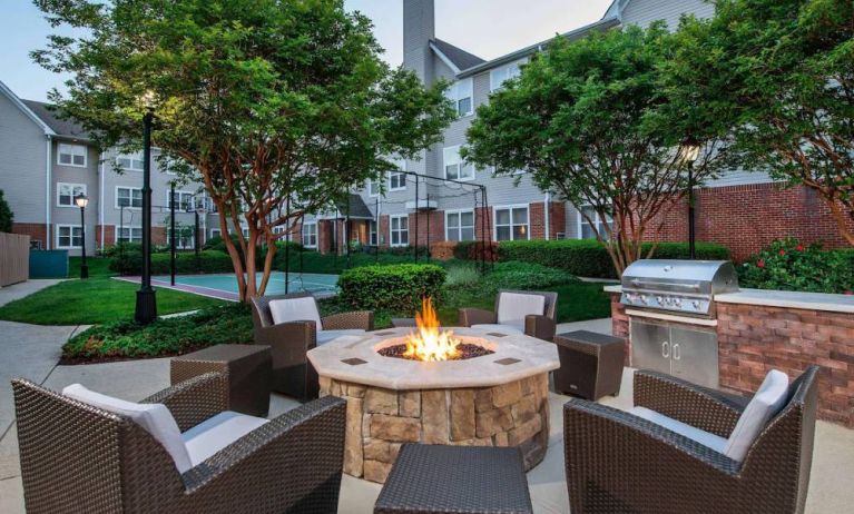 Sonesta ES Suites Baltimore BWI Airport’s fire pit is surrounded by armchairs and coffee tables, with a barbecue conveniently close.