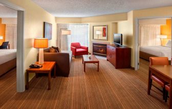 Double bed guest room in Sonesta ES Suites Allentown Bethlehem Airport, including lounge with sofa, TV, armchair, and fireplace.