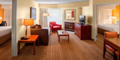 Double bed guest room in Sonesta ES Suites Allentown Bethlehem Airport, including lounge with sofa, TV, armchair, and fireplace.