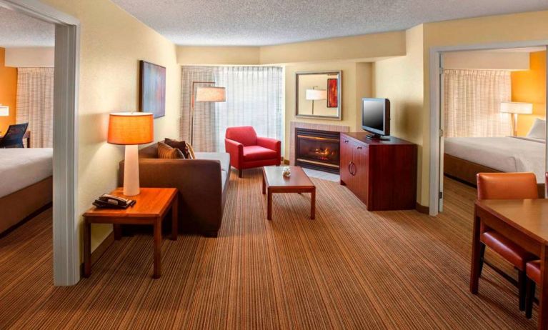 Double bed guest room in Sonesta ES Suites Allentown Bethlehem Airport, including lounge with sofa, TV, armchair, and fireplace.