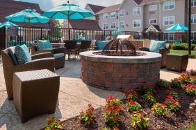 Sonesta ES Suites Allentown Bethlehem Airport’s fire pit has armchairs arranged around it, with the pool and a flowerbed nearby.