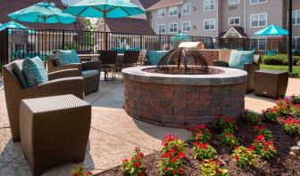 Sonesta ES Suites Allentown Bethlehem Airport’s fire pit has armchairs arranged around it, with the pool and a flowerbed nearby.