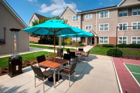 Sonesta ES Suites Allentown Bethlehem Airport’s patio is furnished with shaded tables and chairs.