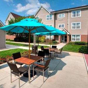 Sonesta ES Suites Allentown Bethlehem Airport’s patio is furnished with shaded tables and chairs.